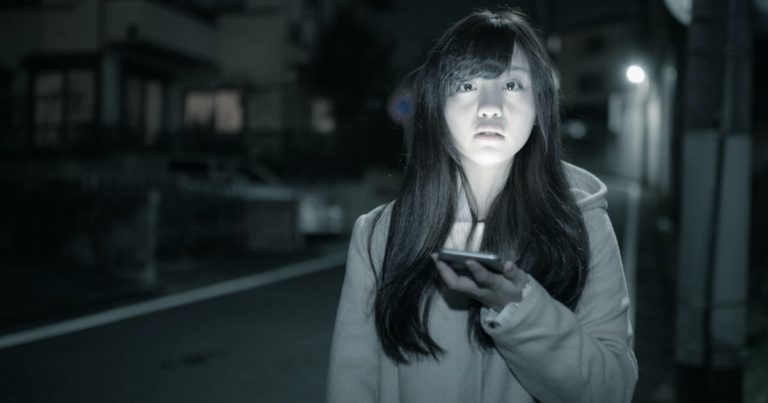 深夜にスマホの明かりで立つ美少女