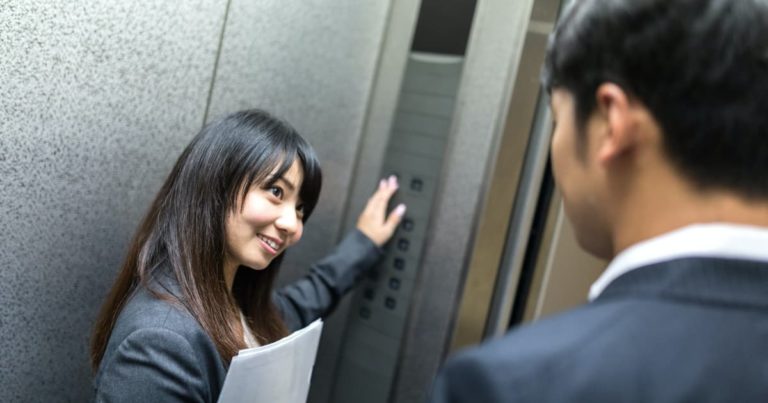 エレベーターのボタンを押す美女