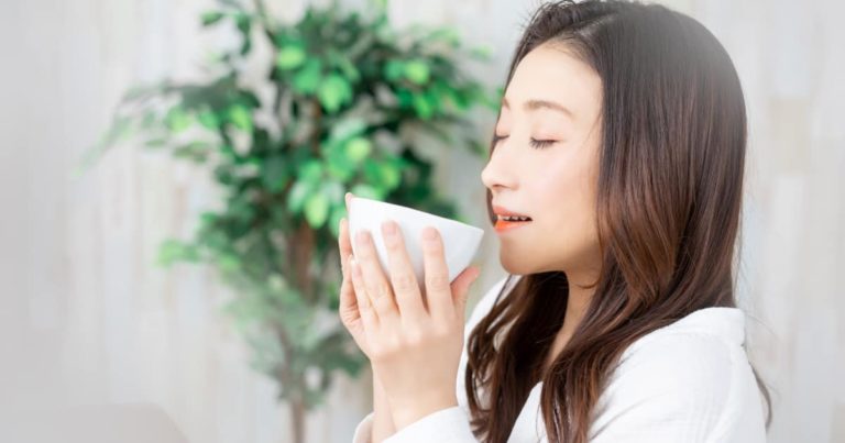 カップの何かを飲む女性