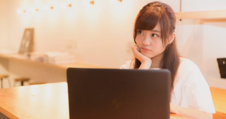 ノートパソコンの前で考える美少女