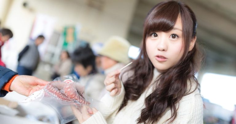 朝市で新鮮なタコを試食する美少女
