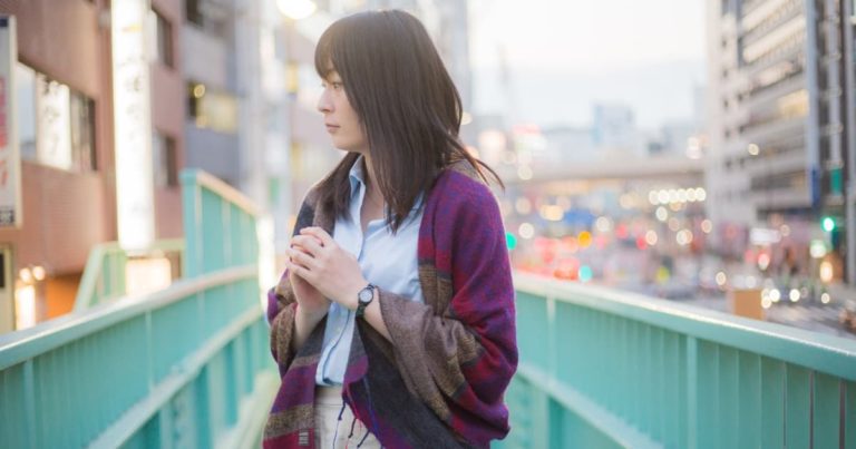 歩道橋の上で立ち止まる女性