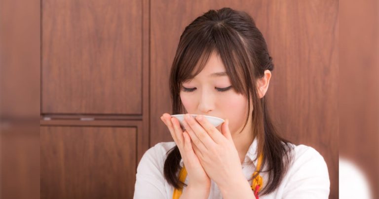 味噌汁の味見をする女性
