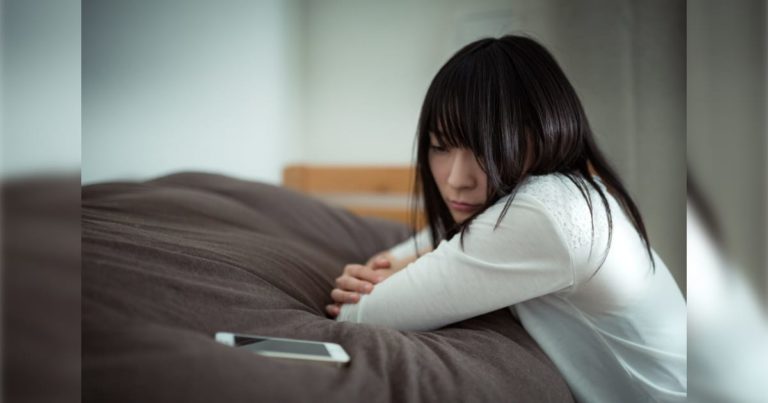スマホを見て悲しい顔をする女性（泣く）