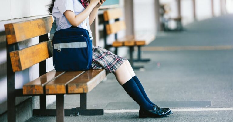 駅のベンチに座る女子高生