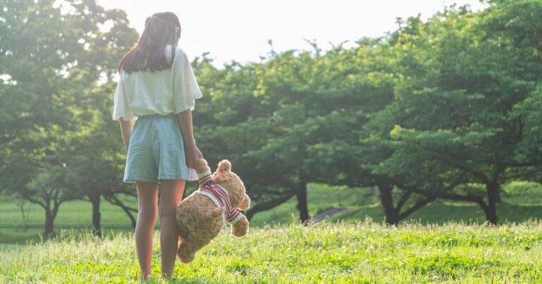 クマのぬいぐるみを持って立つ少女