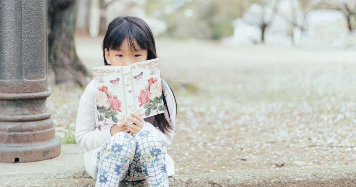 公園に座って本を読む可愛い女の子