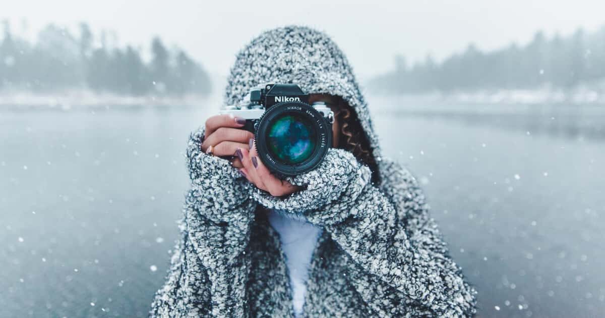 雪の中、ニコンのカメラを構える外国人女性