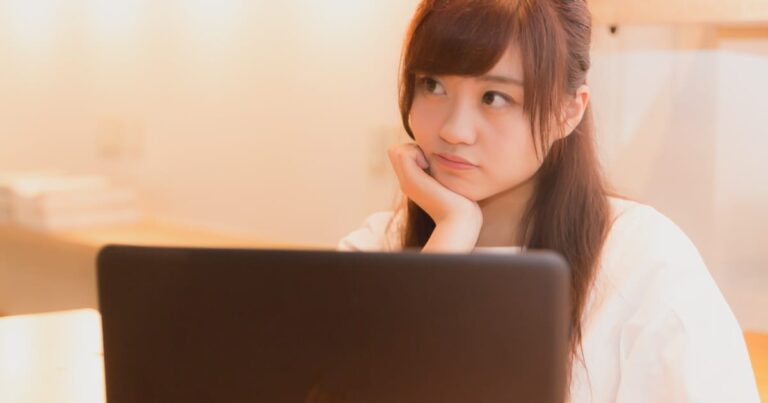 ノートパソコンの前で考える美少女