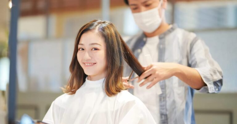 美容院で美容師に髪をカットしてもらう美女