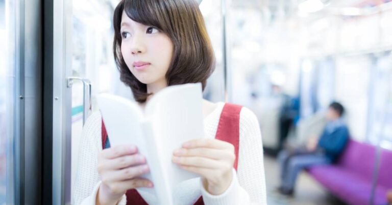 電車のドア脇で本を読む美少女