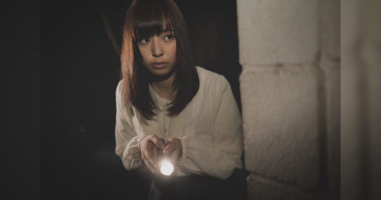 暗闇でライトをかまえる美少女